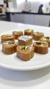 Round pieces of Indian sweet, kaju katli, are arranged on a white plate. Generated image Royalty Free Stock Photo