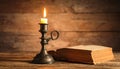 Burning candle in candlestick and old book on wooden table Royalty Free Stock Photo