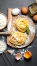 Board with homemade pasta, flour and ingredients on dark table, flat lay Royalty Free Stock Photo