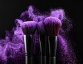 Makeup brushes with purple eye shadow on black background, closeup. Royalty Free Stock Photo