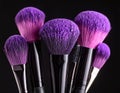 Makeup brushes with purple eye shadow on black background, closeup. Royalty Free Stock Photo