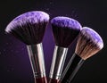 Makeup brushes with purple eye shadow on black background, closeup. Royalty Free Stock Photo