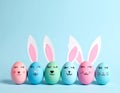 Bright Easter eggs rabbit ears and faces light blue background, banner design Royalty Free Stock Photo