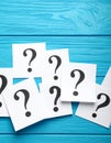 Paper cards with question mark on blue wooden background, top view. Space for text Royalty Free Stock Photo
