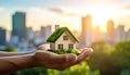 Hands hold a small model house with a green roof resembling grass Royalty Free Stock Photo