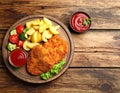 Tasty schnitzels served with potatoes, ketchup and vegetables on wooden table Royalty Free Stock Photo