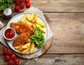 Tasty schnitzels served with potatoes, ketchup and vegetables on wooden table Royalty Free Stock Photo