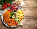 Tasty schnitzels served with potatoes, ketchup and vegetables on wooden table Royalty Free Stock Photo