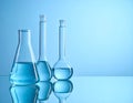 Flasks with liquid on the mirror surface, light blue background, text area. Laborator Royalty Free Stock Photo