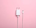 Pink background, USB power adapter and charging cable on flat panel. Royalty Free Stock Photo