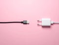 Pink background, USB power adapter and charging cable on flat panel. Royalty Free Stock Photo