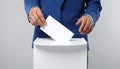 Man putting his vote into ballot box on light grey background, closeup Royalty Free Stock Photo