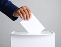 Man putting his vote into ballot box on light grey background, closeup Royalty Free Stock Photo