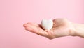 Aesthetic hand gently holds a heart shaped stone against a soft pink background showing love and compassion Royalty Free Stock Photo