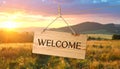 Welcome card. Wooden board with word hanging on rope in countryside Royalty Free Stock Photo