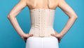 Closeup of woman with orthopedic corset on blue background, back view Royalty Free Stock Photo