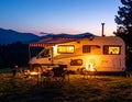 Beautiful camper van with campfire at sunset in mountain nature Royalty Free Stock Photo