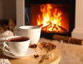 Cup of hot drink near fireplace at home. Space for text Royalty Free Stock Photo