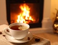 Cup of hot drink near fireplace at home. Space for text Royalty Free Stock Photo