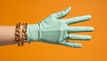 A stylish hand donning a mint-colored glove showcases a chic ring and gold chain Royalty Free Stock Photo