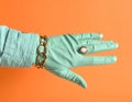 A stylish hand donning a mint-colored glove showcases a chic ring and gold chain Royalty Free Stock Photo