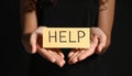 Woman holding piece of paper with word Help on black background, closeup. Domestic Royalty Free Stock Photo