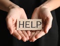Woman holding piece of paper with word Help on black background, closeup. Domestic Royalty Free Stock Photo