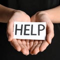 Woman holding piece of paper with word Help on black background, closeup. Domestic Royalty Free Stock Photo