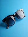 Stylish sunglasses on blue background. Fashionable accessory Royalty Free Stock Photo