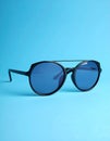 Stylish sunglasses on blue background. Fashionable accessory Royalty Free Stock Photo