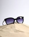 Stylish sunglasses on sand against white background. Space for text Royalty Free Stock Photo