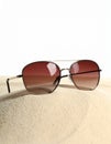 Stylish sunglasses on sand against white background. Space for text Royalty Free Stock Photo