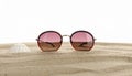 Stylish sunglasses on sand against white background. Space for text Royalty Free Stock Photo