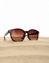 Stylish sunglasses on sand against white background. Space for text Royalty Free Stock Photo