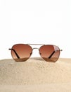 Stylish sunglasses on sand against white background. Space for text Royalty Free Stock Photo