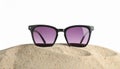 Stylish sunglasses on sand against white background. Space for text Royalty Free Stock Photo