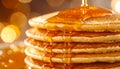 Close up view of fluffy golden pancake stack covered in thick maple syrup flowing down the side with warm golden bokeh background Royalty Free Stock Photo