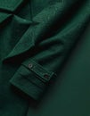 Folded Wool Coat on Matte Dark Green Surface, Sleeve Visible Royalty Free Stock Photo