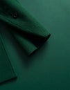 Folded Wool Coat on Matte Dark Green Surface, Sleeve Visible Royalty Free Stock Photo