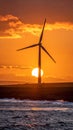 The sun is setting behind the wind turbine, Royalty Free Stock Photo
