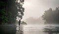 Man fly fishing in fog with trees behind him in morning Royalty Free Stock Photo