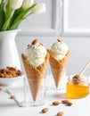 Delicious vanilla ice cream in wafer cones with honey and almonds on white table indor Royalty Free Stock Photo