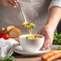 Close-up ladling steaming veggie soup into cup in cozy home kitchen Royalty Free Stock Photo