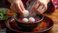 Hands placing mochi into warm red bean soup bowl with soft steam Royalty Free Stock Photo