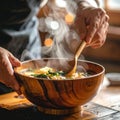 Hands stirring hot miso soup in wooden bowl with rising steam, cozy kitchen Royalty Free Stock Photo