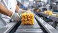 Close-up of hand placing snack packs on belt in industrial packaging area Royalty Free Stock Photo