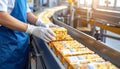 Close-up of hand placing snack packs on belt in industrial packaging area Royalty Free Stock Photo