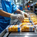 Close-up of hand placing snack packs on belt in industrial packaging area Royalty Free Stock Photo
