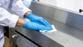 Close-up of worker cleaning polished metal conveyor with sanitizer cloth Royalty Free Stock Photo