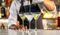 Barman pouring cold martini into glasses on counter, closeup Royalty Free Stock Photo